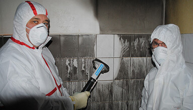Mitarbeiter von Korrekt reinigen einen Brandschaden auf einer Wand.